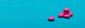 Bright pink pills on dark blue coloured background. Medication and prescription pills web banner.