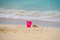 Pink toy beach pail in sand