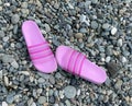 Bright pink slippers are on the pebble beach. Summer walk, sea tourism Royalty Free Stock Photo