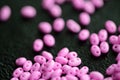 Bright pink twin beads scattered on a dark surface