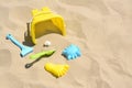 Bright plastic bucket, rake and shovel on sand. Beach toys. Space for text Royalty Free Stock Photo