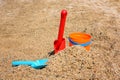 Bright plastic children`s beach toys - bucket and shovels on sand near sea Royalty Free Stock Photo