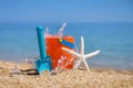 Bright plastic children`s beach toys and a starfish on sand near sea. Royalty Free Stock Photo