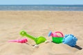 Bright plastic rake and shovel on sand near sea. Beach toys. Space for text Royalty Free Stock Photo