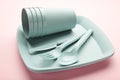 Bright plastic reusable tableware on a pink background