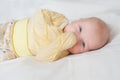 Bright portrait of cute baby with fingers in mouth in white bed Royalty Free Stock Photo