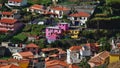 Bright purple colored house located on a slope in residential area surrounded by buildings.