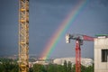 A bright rainbow in the big city. Crane and building construction site