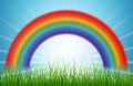 Bright rainbow blue sky with rising sun and green grass