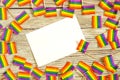 Bright rainbow gay flag on wooden background, paper confetti top view with space for text, mocup, copy space. LGBT community.