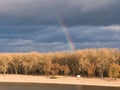 Bright rainbow over trees against dark sky Royalty Free Stock Photo
