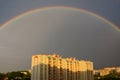 A bright rainbow in the sky after a spring rain over a residential area of high-rise buildings in the city.