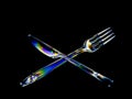 Bright rainbow stress patterns show in transparent plastic cutlery. Polarised light on a dark background. Royalty Free Stock Photo