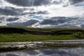 Bright rays of the sun breaking through the clouds in the sky illuminate the hill. Royalty Free Stock Photo