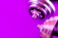 Bright real working dumbbells from several parts on a violet background.