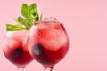 Bright red alcoholic shots in two wineglasses with blueberry, ice cubes, green mint closeup, top section on pastel pink color. Royalty Free Stock Photo