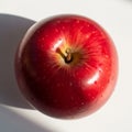 A bright red apple sits on a white background, with a smooth Royalty Free Stock Photo
