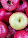 Bright red apples and pomegranates closeup with standout green apple