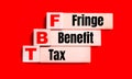 On a bright red background, light wooden blocks and cubes with the text FBT Fringe Benefit Tax Royalty Free Stock Photo