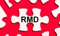 On a bright red background, white puzzles. In one of the pieces of the puzzle, the text RMD Required Minimum Distributions Royalty Free Stock Photo