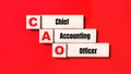 On a bright red background, wooden cubes and blocks with the text CAO Chief Accounting Officer. Manufacturing of wooden toys Royalty Free Stock Photo