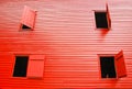 Bright red barn wall with four asymmetrical open windows with shutters Royalty Free Stock Photo