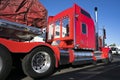 Bright red big rig classic American semi truck with flat bed semi trailer carry commercial cargo covered and fixed by slings stan Royalty Free Stock Photo