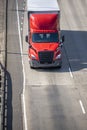 Bright red big rig semi truck transporting commercial cargo in dry van semi trailer driving on the road Royalty Free Stock Photo