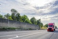 Bright red big rig semi truck transporting goods in dry van semi trailer running on the straight wide highway road with concrete Royalty Free Stock Photo