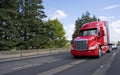 Bright modern long haul big rig semi truck with semi trailer moving on the green road Royalty Free Stock Photo