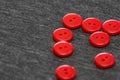 Bright red buttons. Gray fabric. Blurred background. The concept of the clothing industry and decor Royalty Free Stock Photo