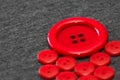 Bright red buttons. Gray fabric. Blurred background. The concept of the clothing industry and decor Royalty Free Stock Photo