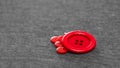 Bright red buttons. Gray fabric. Blurred background. The concept of the clothing industry and decor Royalty Free Stock Photo