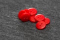 Bright red buttons. Gray fabric. Blurred background. The concept of the clothing industry and decor Royalty Free Stock Photo
