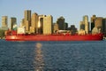 Bright red cargo ship travels in front of Boston Harbor and the Boston skyline at sunrise as seen from South Boston, Massachusetts Royalty Free Stock Photo