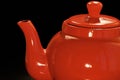 Bright red ceramic teapot or brewing teapot on a black background. Small kettle, afternoon tea-drink hot tea Royalty Free Stock Photo
