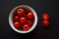 Bright Red Cherry Tomatoes, White Bowl, Two Red Half-fractions, Black Table Royalty Free Stock Photo