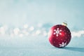 Bright Red Christmas Bauble in Winter Wonderland. Blue Christmas background with defocused christmas lights. Royalty Free Stock Photo