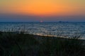 Bright red circle of sun yellow pink orange dawn at sea  coast, shore with waves, morning Royalty Free Stock Photo