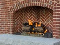 Cheerful fire burns in brick fireplace heating outdoor space Royalty Free Stock Photo