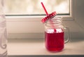 Bright red compote in the original glass mug, autumn composition on the window. Hugue style, autumn style, autumn still life Royalty Free Stock Photo