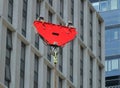 A bright red crane hook and pulley lifting a suspended metal chain on a construction site with urban modern buildings Royalty Free Stock Photo