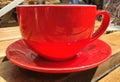 Up close red cup and saucer on a wooden bench in the sun. Royalty Free Stock Photo