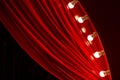 Bright red curtain with multiple small white bulbs along the edge hanging down