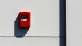 Bright red fire alarm pull station mounted on white wall ensuring safety in modern building construction Royalty Free Stock Photo