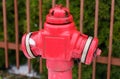 A bright red fire hydrant stands on the street near the fence Royalty Free Stock Photo