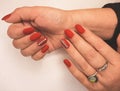 Bright red gel polish on short nails with silver design and rhinestones. An attractive manicure with a silver stripe design with d