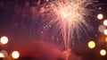 Bright red and gold fireworks exploding in the night sky with blurred lights in the background Royalty Free Stock Photo
