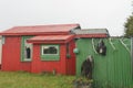 Bright red and green holiday home or batch in remote New Zealand coastal town