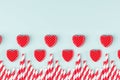 Bright red hearts and cocktail straws as decorative border on mint pastel paper background. Valentine`s day youth design concept.